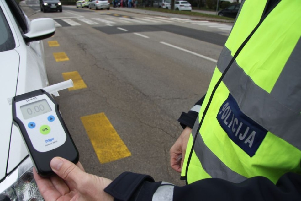Policist v rokah drži alkotest.