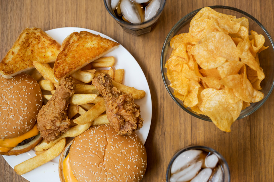 Na mizi je polno mastne in nezdrave hrane.