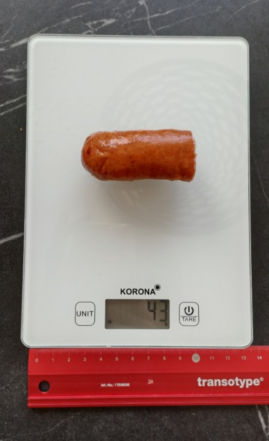 Hrenovka na živilski vagi. Tehnica kaže koliko kilogramov teže.
