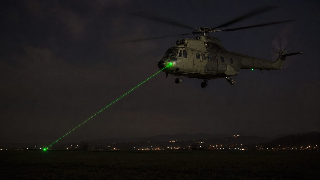 Ilustrativna podoba helikopterja med nočnim poletom, ki ga z zelenim laserjem osvetljuje neznanec s tal.