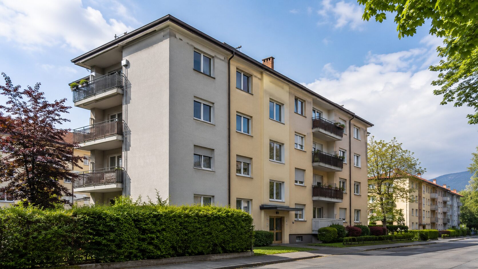 Stanovanjski blok z balkoni in urejeno okolico v slovenskem stanovanjskem naselju.