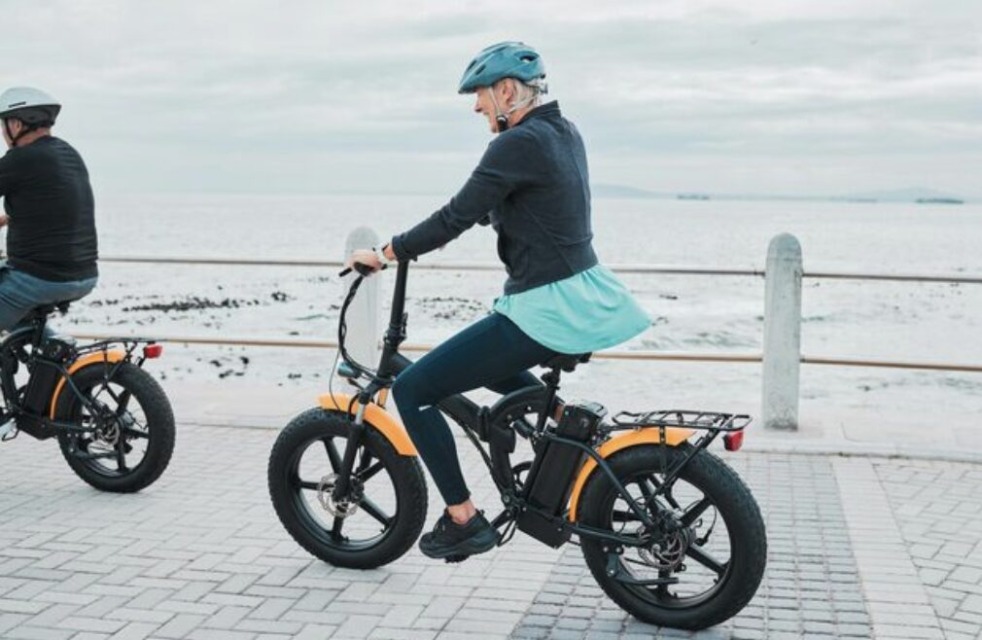 Oseba vozi električno kolo ob peščeni plaži