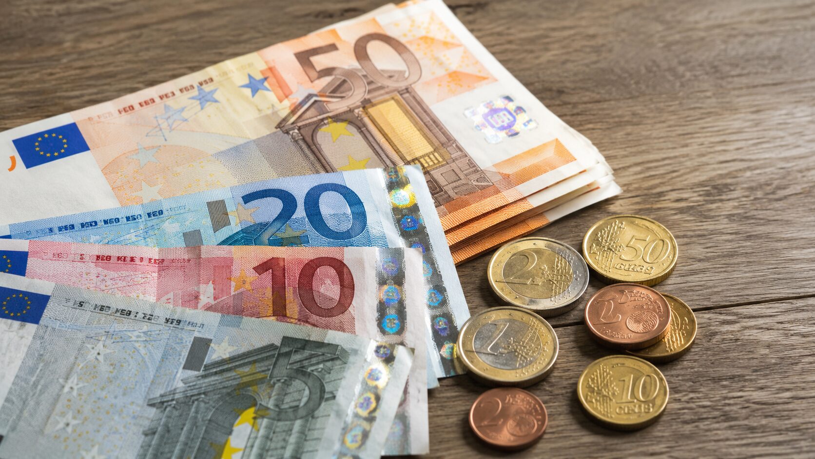 Evrski bankovci in kovanci ponazarjajo izplačilo letnega dodatka za upokojence.