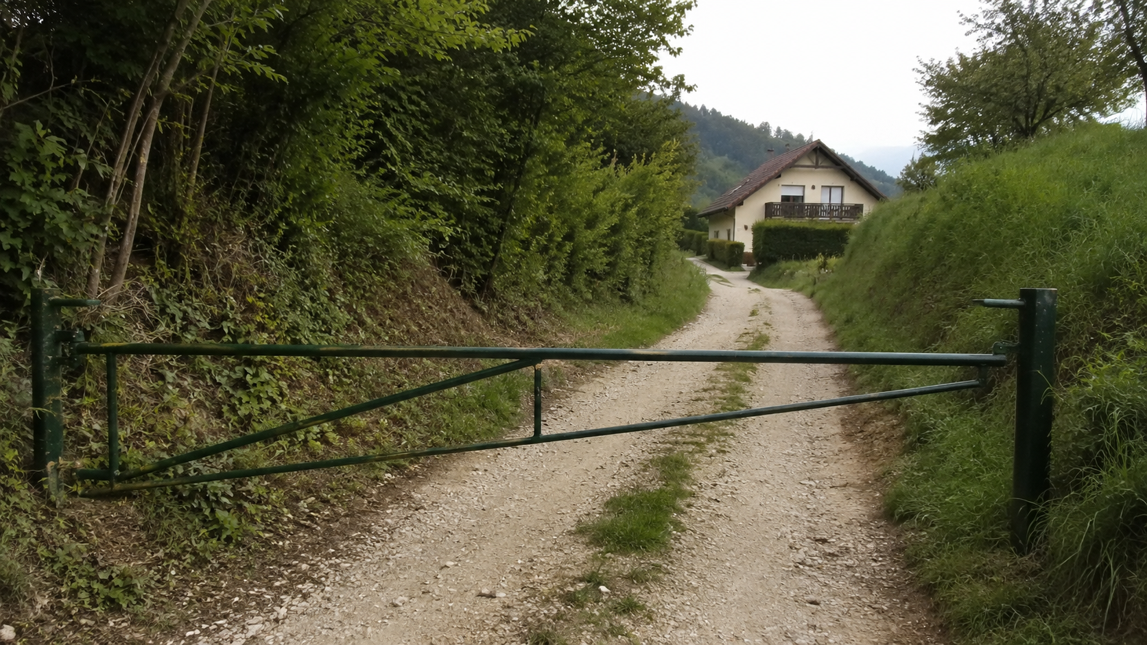 Zaprta služnostna pot z zapornico in hišo v ozadju